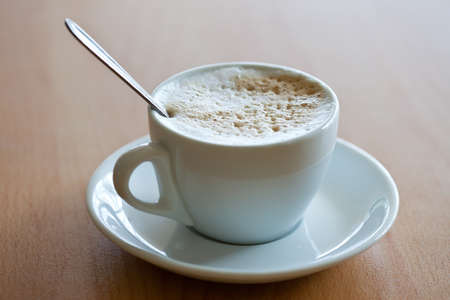 white cup of coffee with crema on the wood table
