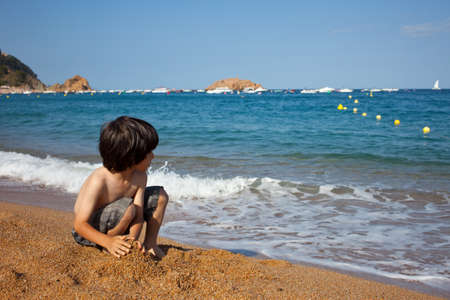 child builds a sand castle on the shore of  seaの写真素材