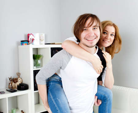 Man carrying girlfriend on his back in homeの写真素材