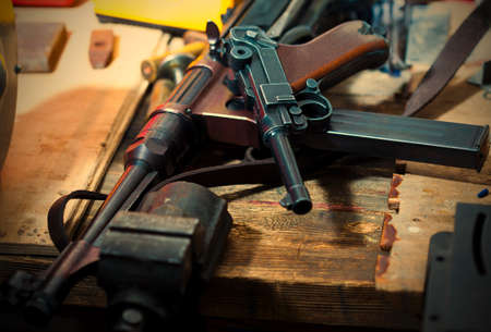Luger pistol and mashinegun MP 38 in gunsmith on old wooden surface.の写真素材