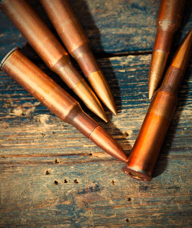 rifle cartridges on aged wooden surface.の写真素材