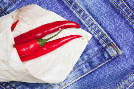 red hot chili peppers in paper bags on a jeans backgroundの写真素材