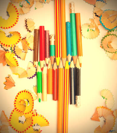 set of colored pencils to draw with the shavings on a white background. instagram image retro style