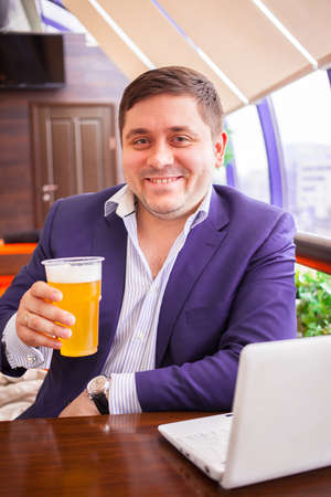 smiling businessman with beer after a hard day in the cafeの写真素材