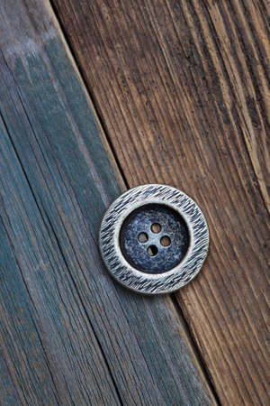 one Button for clothes on an old wooden surface of board