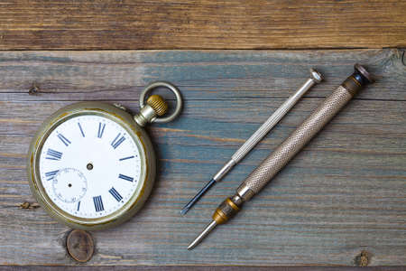 broken vintage watch without hands and two  on the wooden surface