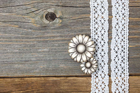 still life with vintage metal buttons flowers and lace ribbons on old wooden surface
