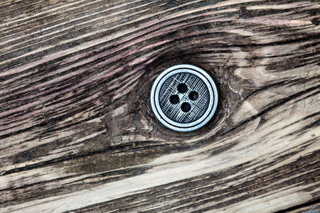 Vintage silvery button on aged textured boardの写真素材