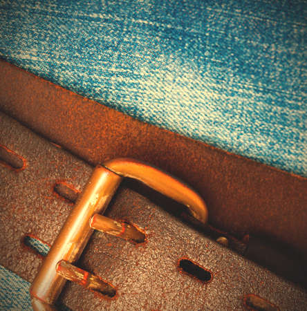clasped aged leather belt on jeans background