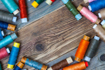 Vintage spools with multi colored threads on old tailoring table with copy spaceの写真素材