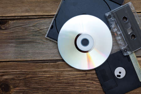 old storage media - CD, DVD, tape and diskette on textured surface of old tableの写真素材