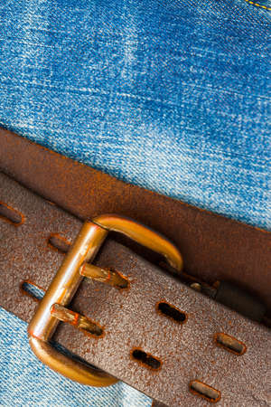 clasped aged leather belt on jeans backgroundの写真素材