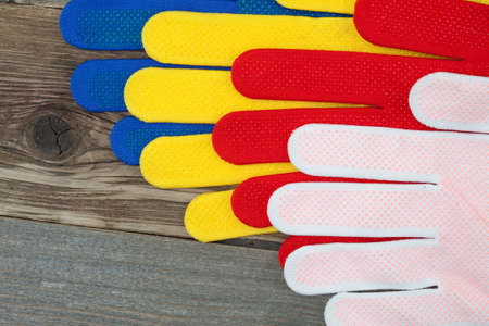 four colored construction gloves on an old workbench with copy space