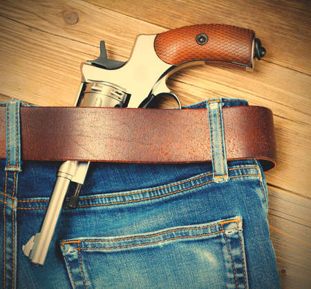 revolver in his belt of blue jeans.  image filter retro style