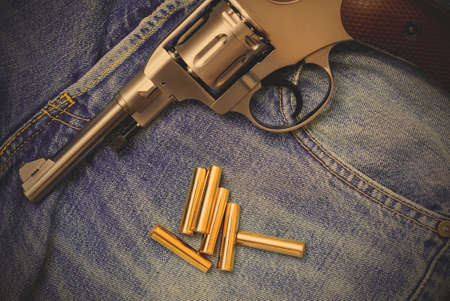 Nagan revolver with ammunition on blue jeans background, close-up, part of.  image filter retro styleの写真素材