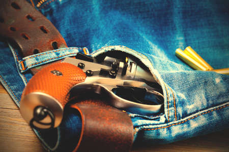 silver revolver nagant in the pocket of old blue jeans. close up.  image filter retro styleの写真素材