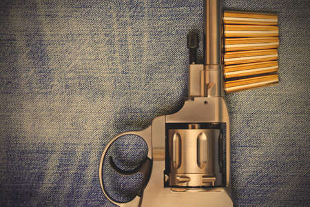 Nagan revolver with cartridges on blue jeans background, close-up, part of.  image filter retro