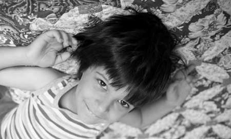 Smiling boy lying, arms outstretched, soft focusの写真素材