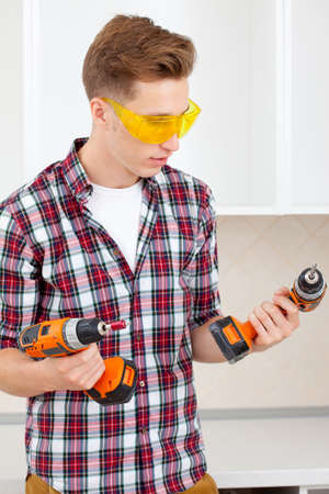 smiling repairman in yellow safety glasses selects toolの写真素材