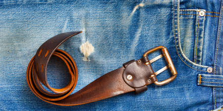 a rolled-up vintage belt on old blue jeansの写真素材
