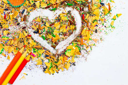 heart, multicolored pencils and varicolored wooden shavings on the white backgroundの写真素材