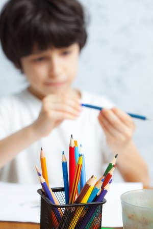 pencil holders with pencil in focus. boy chooses a pencil for drawing on the backgroundの写真素材