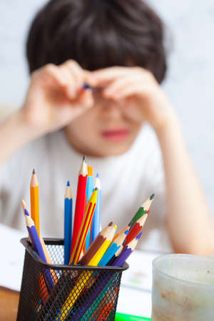 colored pencils to draw in a holder and a child on the background. focus on pencils