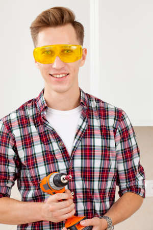 repairman in eyeglasses and with a drill in his handsの写真素材