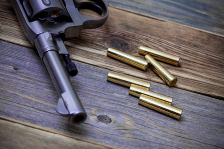 Nagan revolver with cartridges on aged wood background, close-up, part ofの写真素材