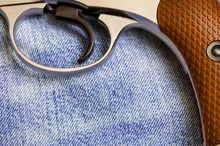 part of an vintage nagan revolver with the hammer  and handle on the background of denimの写真素材