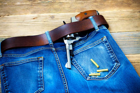 vintage revolver in his leather belt of blue jeansの写真素材