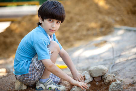 boy builds a house out of stones and sandの写真素材