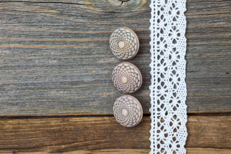 set of three vintage buttons and lace ribbon on the aged wooden surface