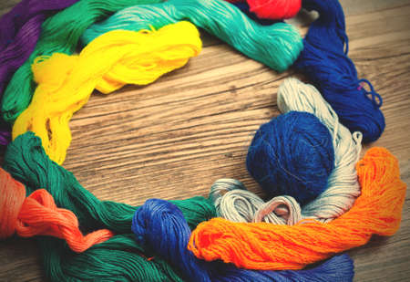 varicolored threads floss for embroidery on old textured boards of tailor%u2019s table. shallow depth of field. image filter retro styleの写真素材