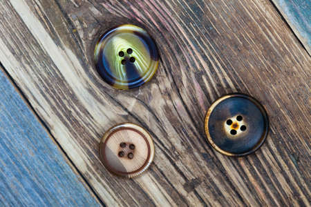 three vintage buttons on old textured wooden surface
