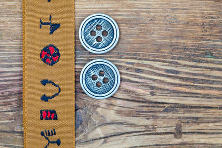vintage brown band with embroidered ornaments and old button on a textured surface aged boardsの写真素材