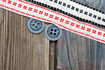 vintage ribbons with embroidered ornaments and old button on a textured surface aged boards