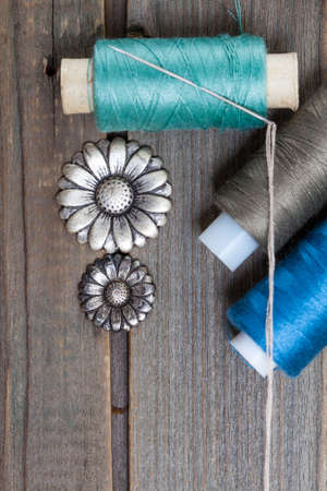 two vintage buttons flowers and spools with threads on old wooden surface