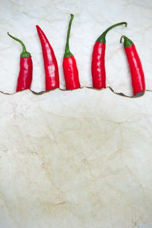 fiery red chili peppers under a sheet of paper with the scorched edge