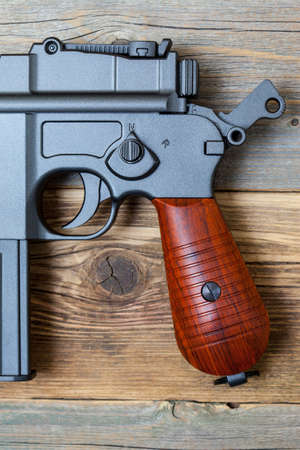 vintage pistol gun with the hammer cocked on a background of old boards. fragment
