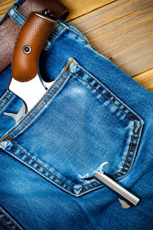 silver revolver nagant with brown handle in the pocket of old blue jeans. close upの写真素材