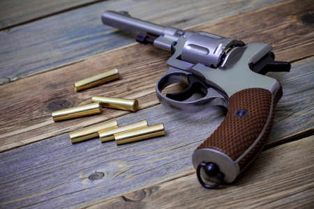 silvery pistol with cartridges on aged wood background, close-up, part ofの写真素材
