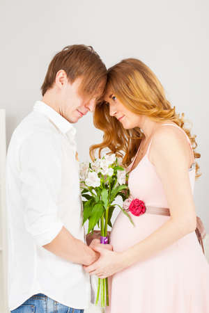 Happy future parents together facing each other with a bouquet of flowersの写真素材