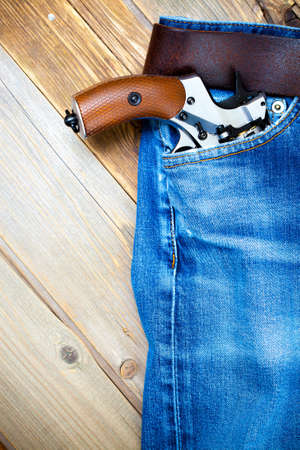 revolver nagant in the pocket of old blue jeans on the aged wooden boardsの写真素材