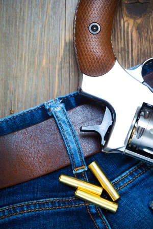 silvery revolver nagant with cartridges on old blue jeans background, close upの写真素材