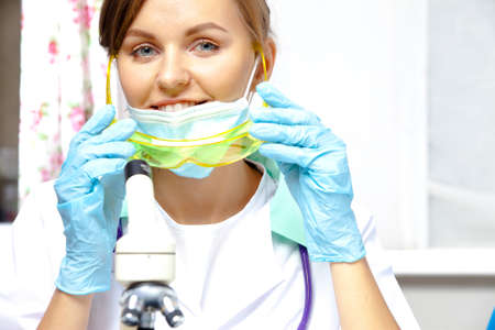young woman  researcher holding in hands goggles, smiling and looking into the lensの写真素材