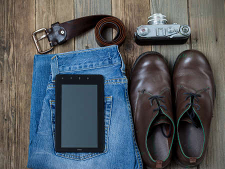 traveler set with a digitizer, leather belt, rangefinder camera, jeans and boots on old boards of tableの写真素材