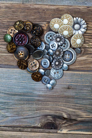 Heart from vintage colored buttons on the old textured boards