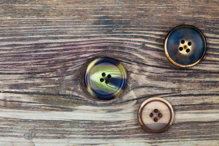 three old buttons on old textured wooden surfaceの写真素材