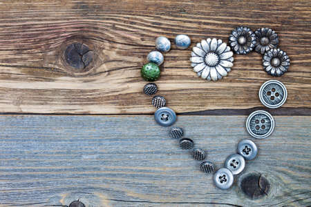 vintage buttons heart on old textured boards of ancient tailor table with copy space